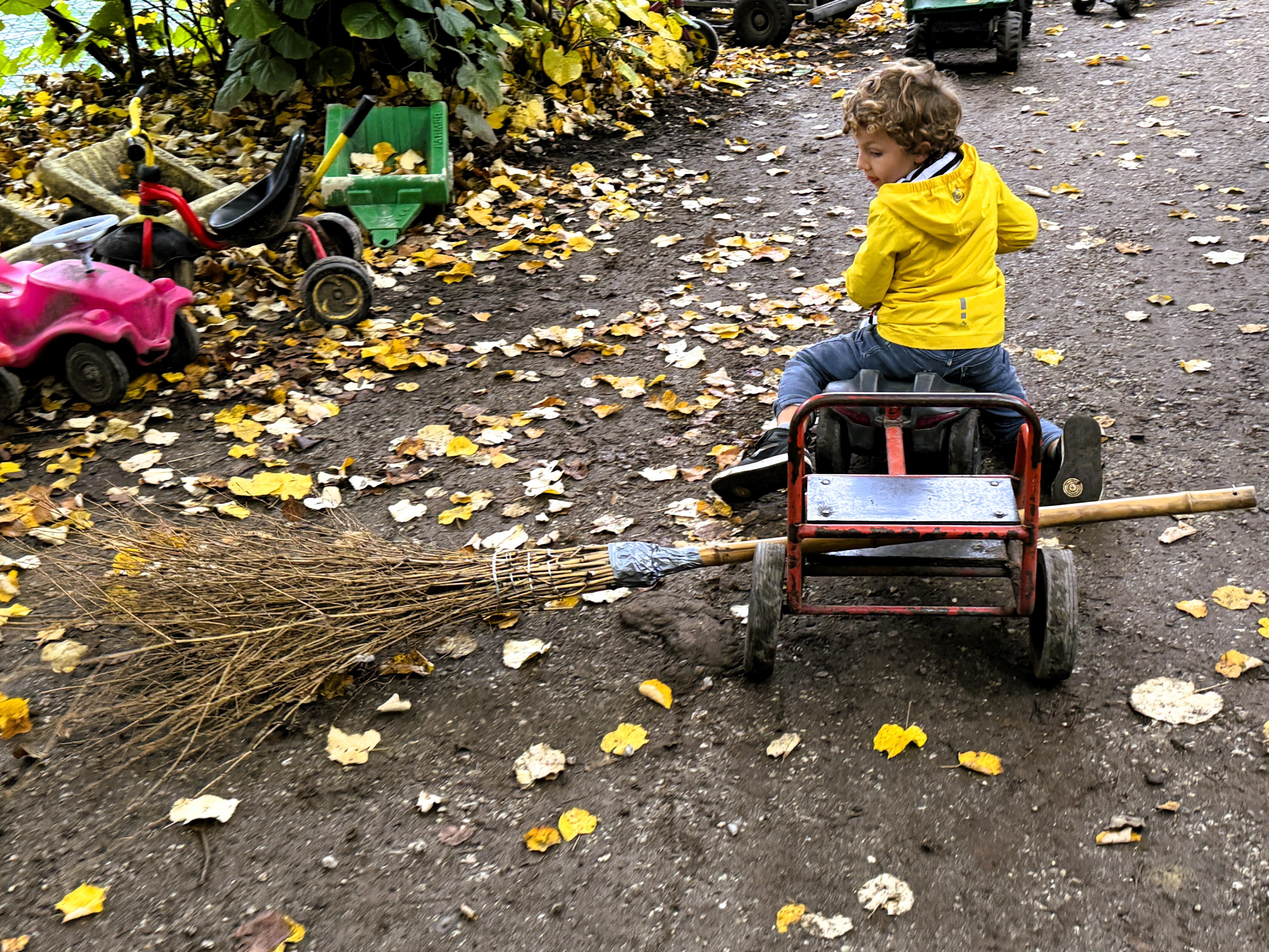 Symbolbild DOK Herbst, Kind wischt Blätter auf dem Spielplatz Längmuur