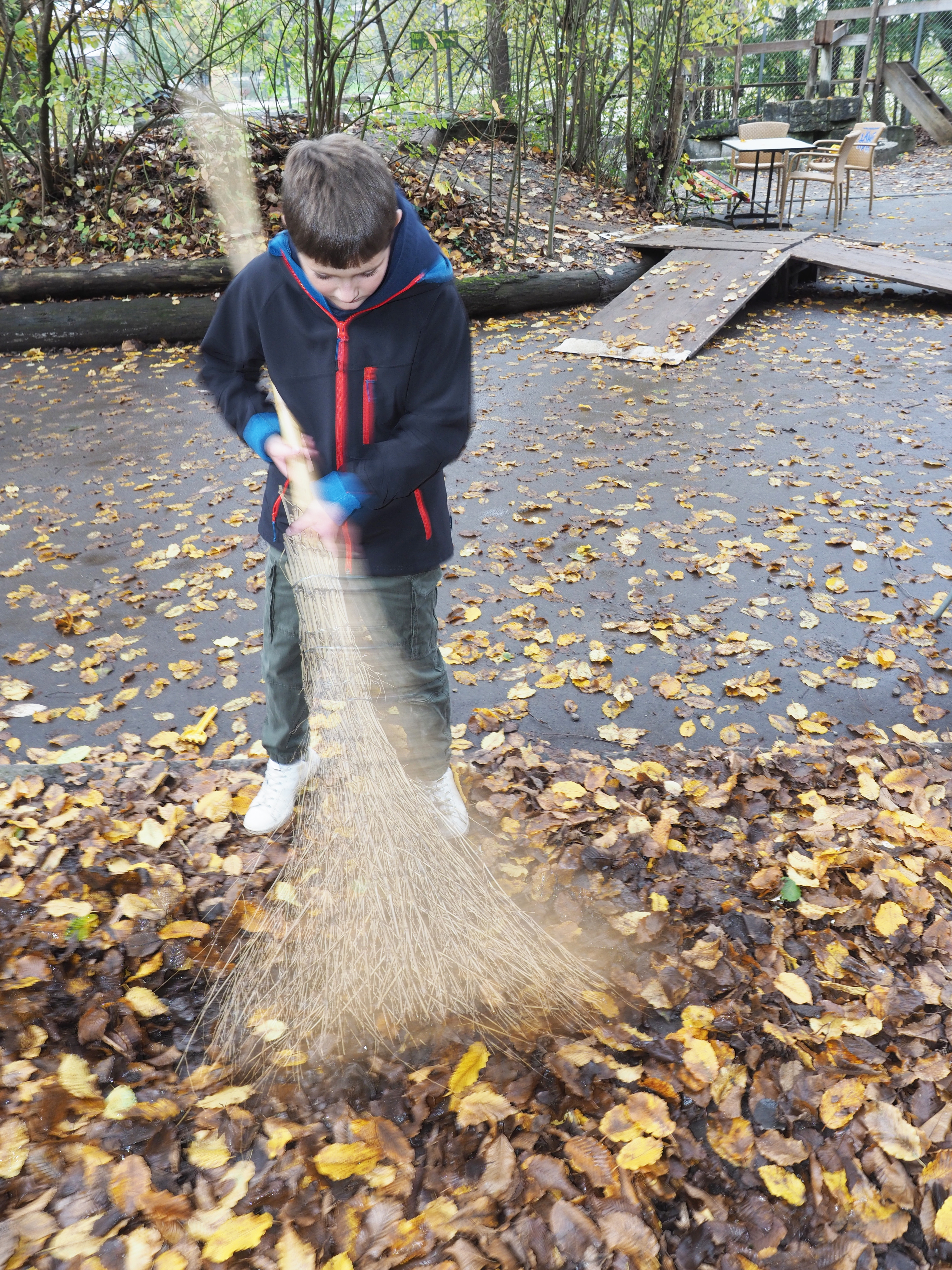 Symbolbild DOK Herbst, Kind wischt Blätter auf dem Spielplatz Längmuur